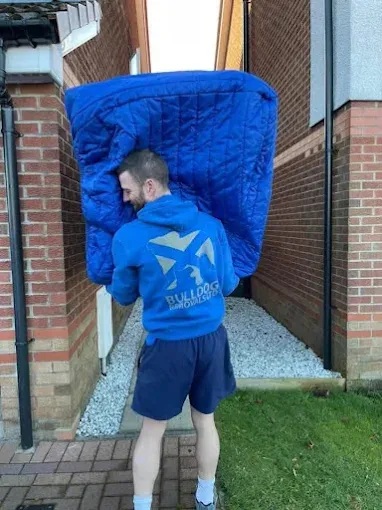 A team member carrying a blanket-wrapped item from a property